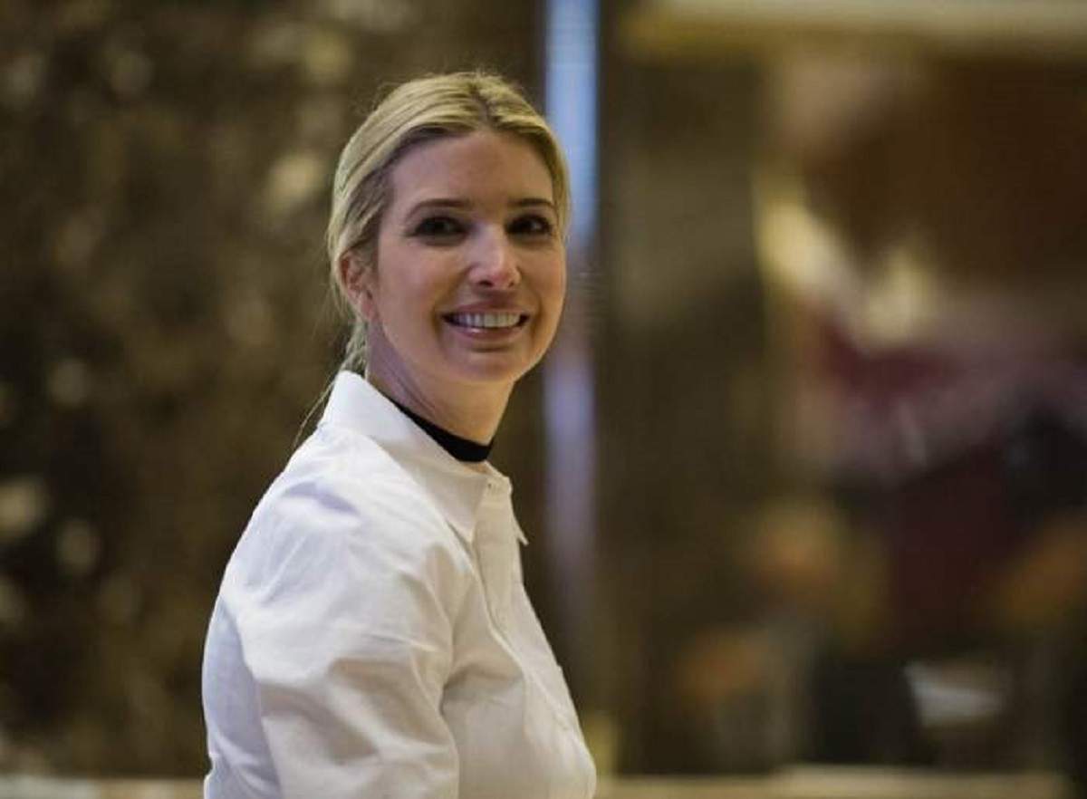 Ivanka Trump zâmbește larg, este îmbrăcată cu o haină albă și are părul prins