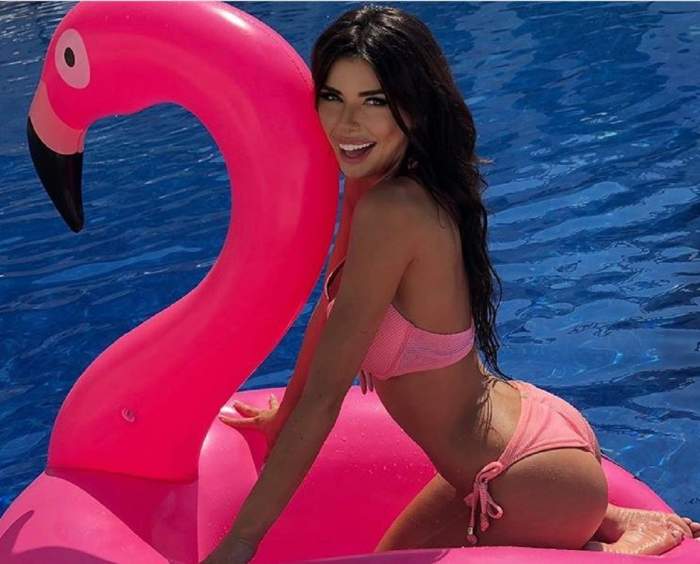 Ioana Filimon este în piscină și stă pe un colac în formă de flamingo, îmbărcată cu un costum de baie roz