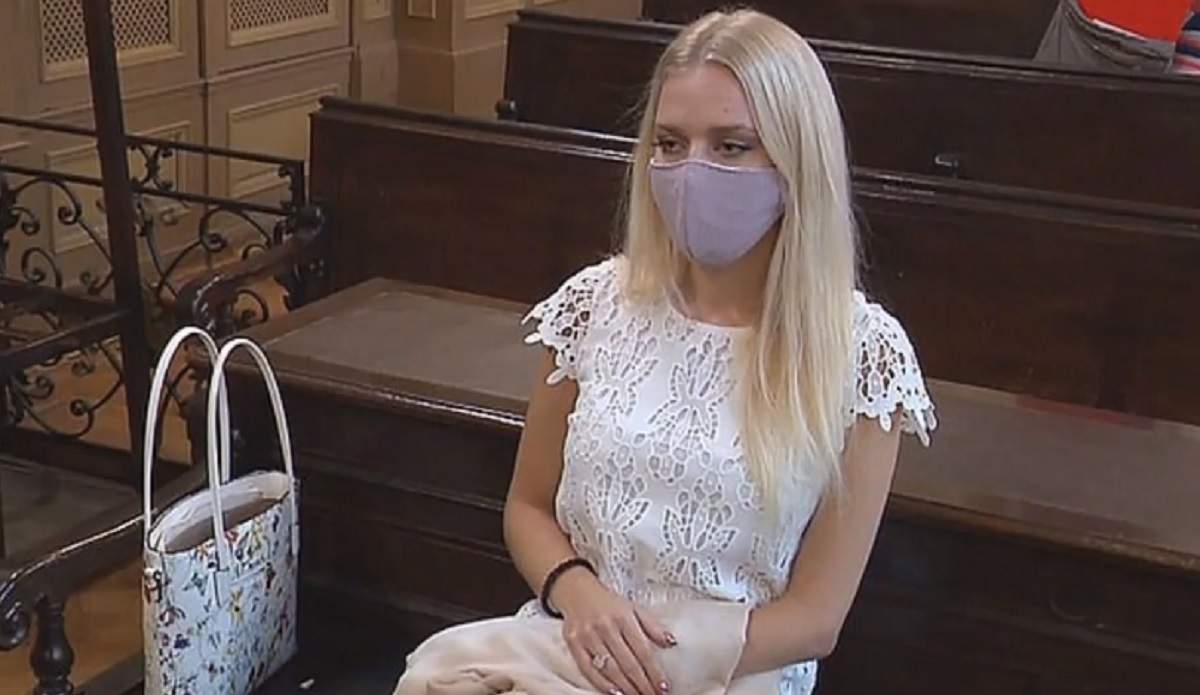 Julija Adlesic, tânăra care și-a tăiat mâna pentru asigurare, în sala de judecată, cu mască și o rochie albă