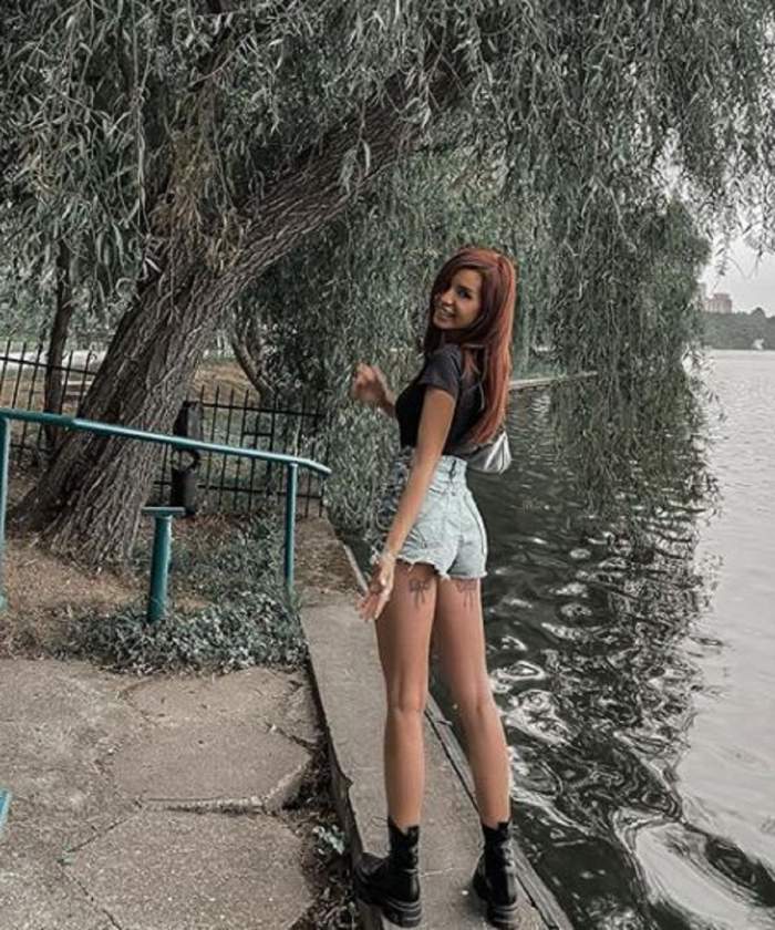 Carmen Grebenișan este în parc, lângă lac. Poartă un tricou negru și pantaloni scurți cu bocanci