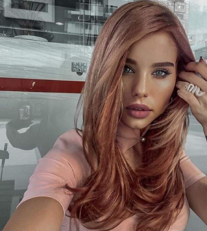 Carmen Grebenișan, într-un selfie. Poartă un tricou roz, are părul desprins și ține o mână în păr