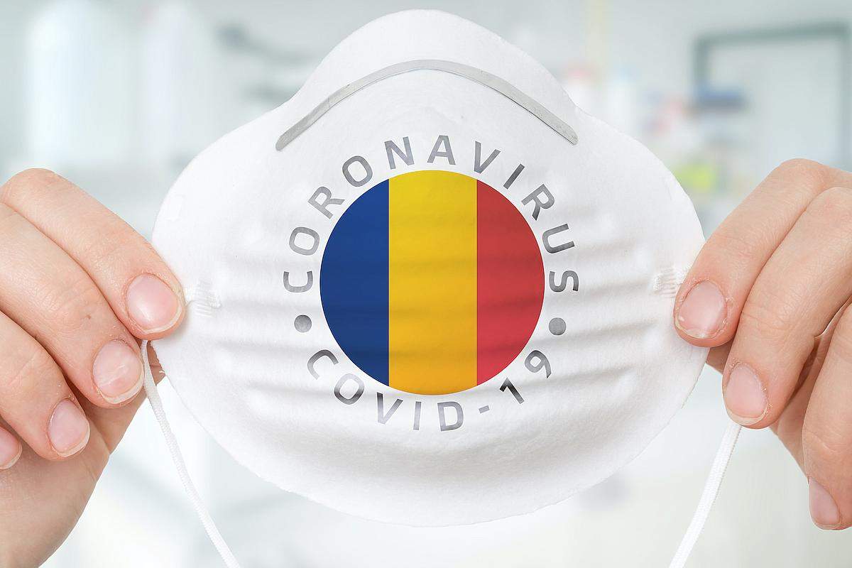 O persoană ține o mască de protecție cu steagul României