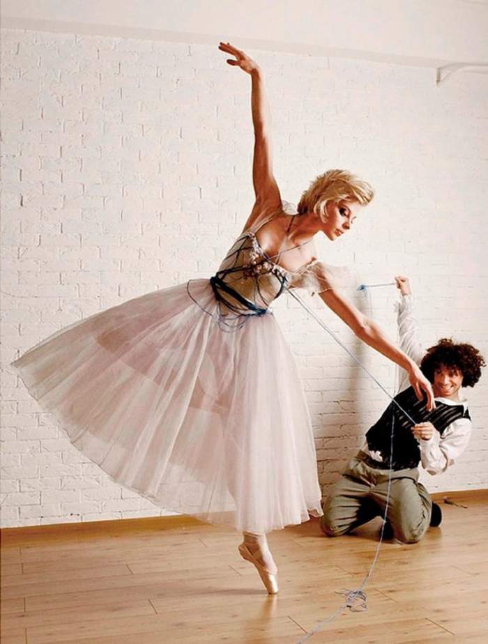 Balerina Olga Damina într-o poziție de balet, stă într-un picior și ține brațele sus