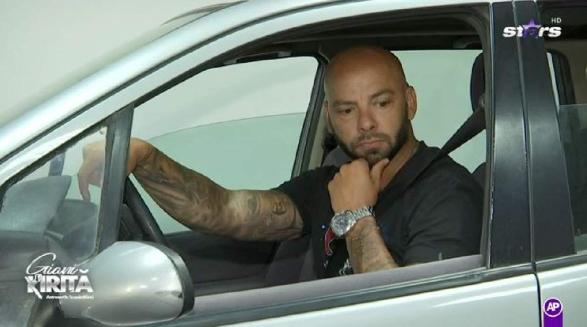 Giani Kiriță la volanul unei mașini. Sportivul e îmbrăcat într-un tricou negru, ține mâna pe volan și poartă un ceas.