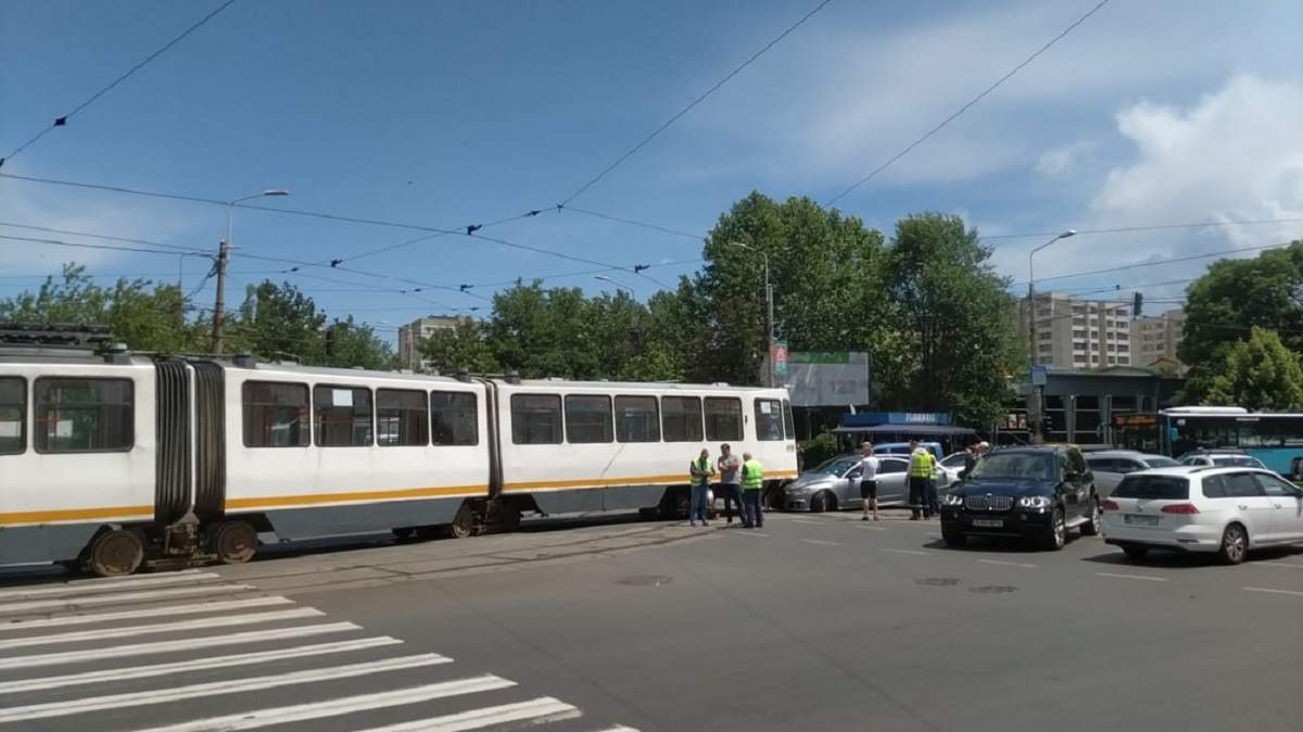 Tramvai din București în intersecție, mașini și oameni în veste reflectorizante
