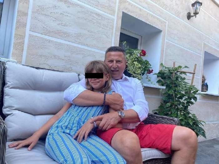 Traian Ogâgău este pe o canapea albă, alături de fiica sa