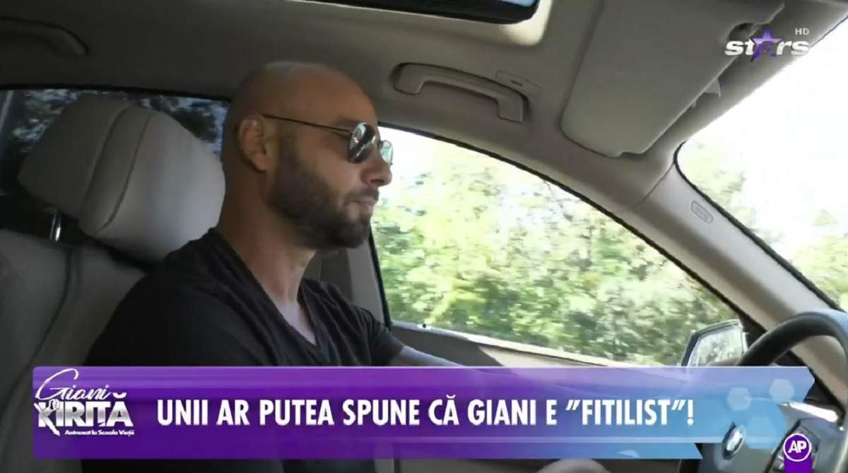 Giani Kiriță se află la volanul mașinii sale. Vedeta poartă un tricou negru, niște ochelari la ochi și vorbește la telefon cu mama lui