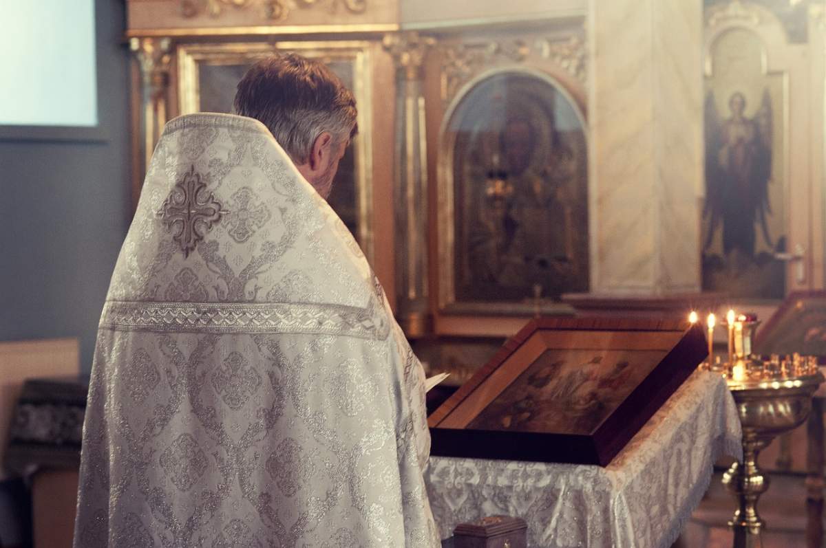 Fotografie cu un preot, în bisrerică, în timp ce se ruga