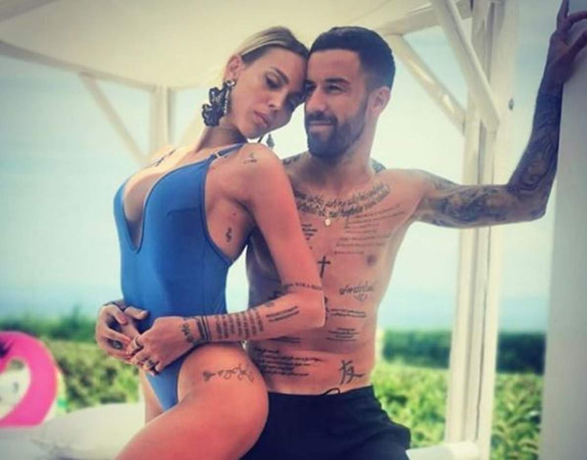 Lena Enache e îmbrăcată într-un costum de baie sexy, albastru și are părul prins. Gabi Enache poartă un short negru și îți ține partenera la piept.