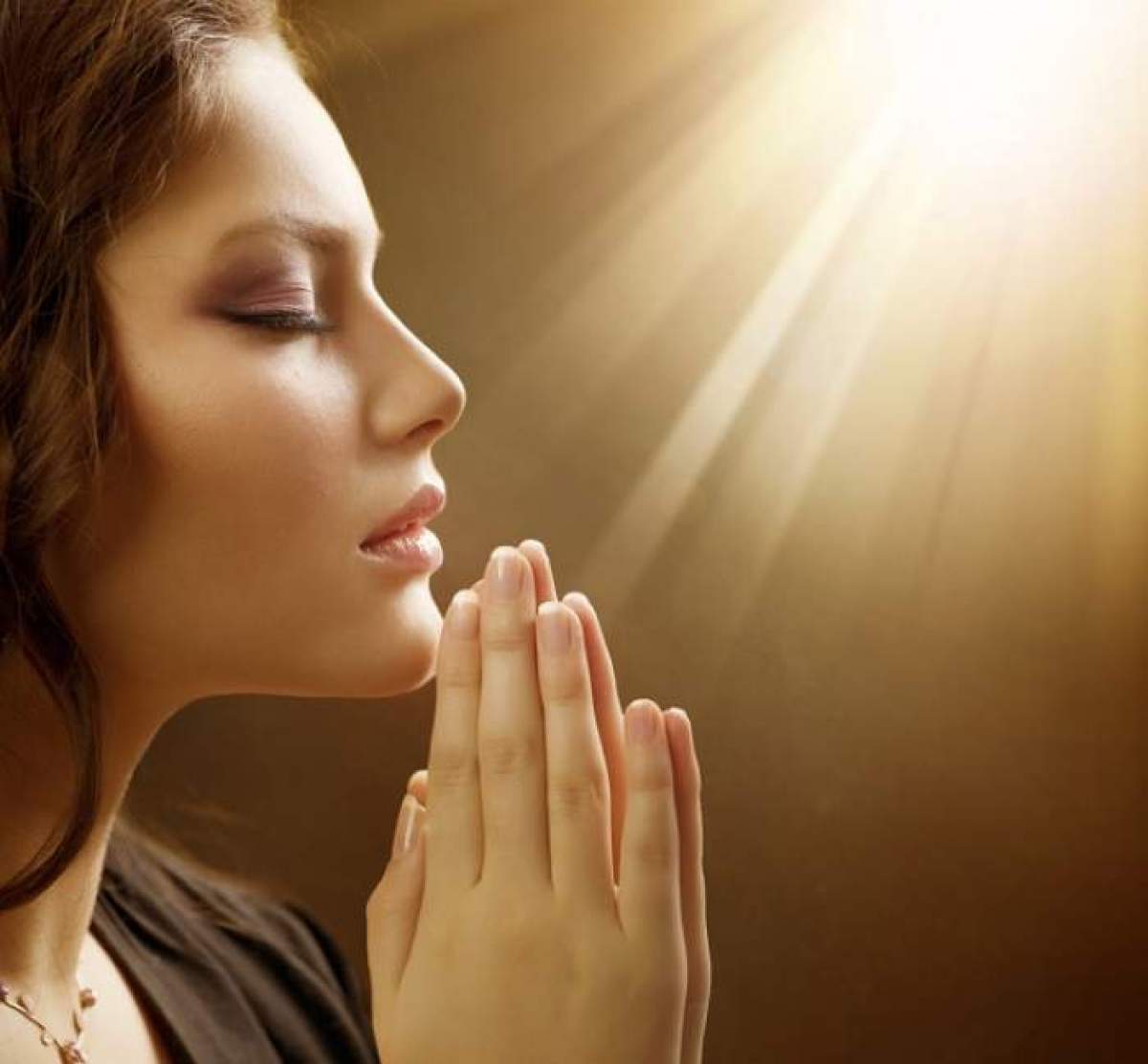 O femeie se roagă în lumina soarelui