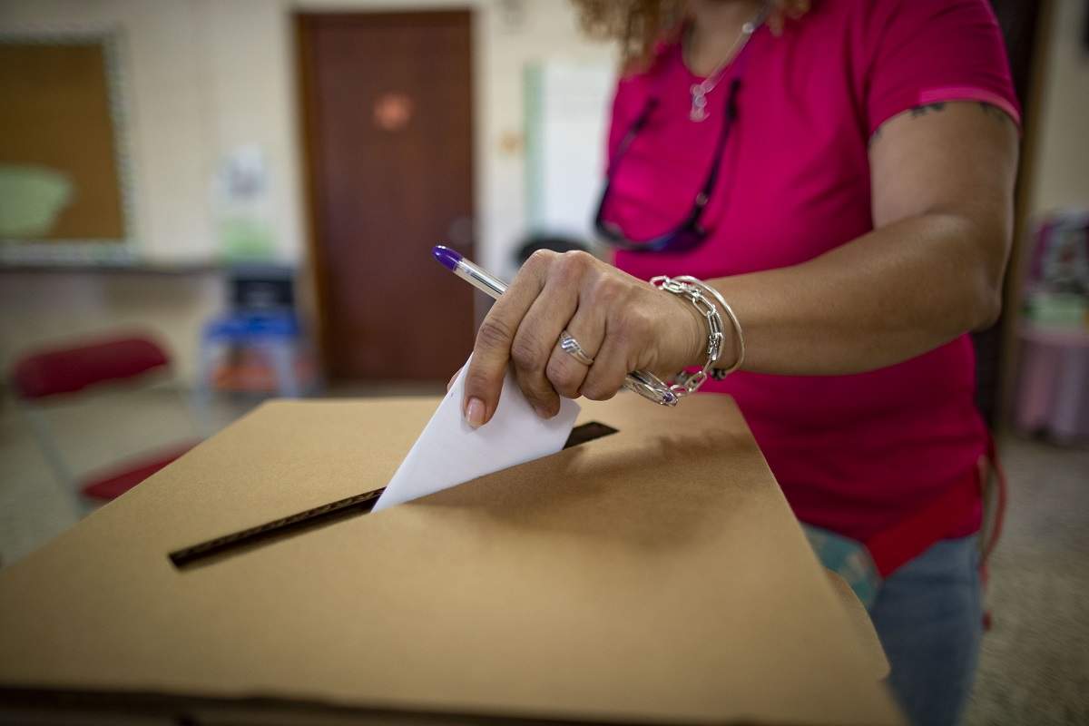 Femeie în tricou roz introduce vot în urnă la alegerile din Puerto Rico