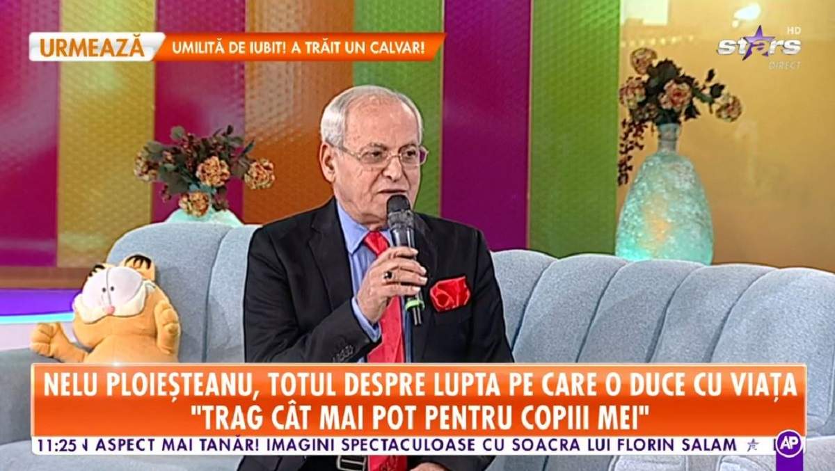 Nelu Ploieșteanu pe canapeaua de la Antena Stars. Artistul poartă un costum negru și o cravată roșie