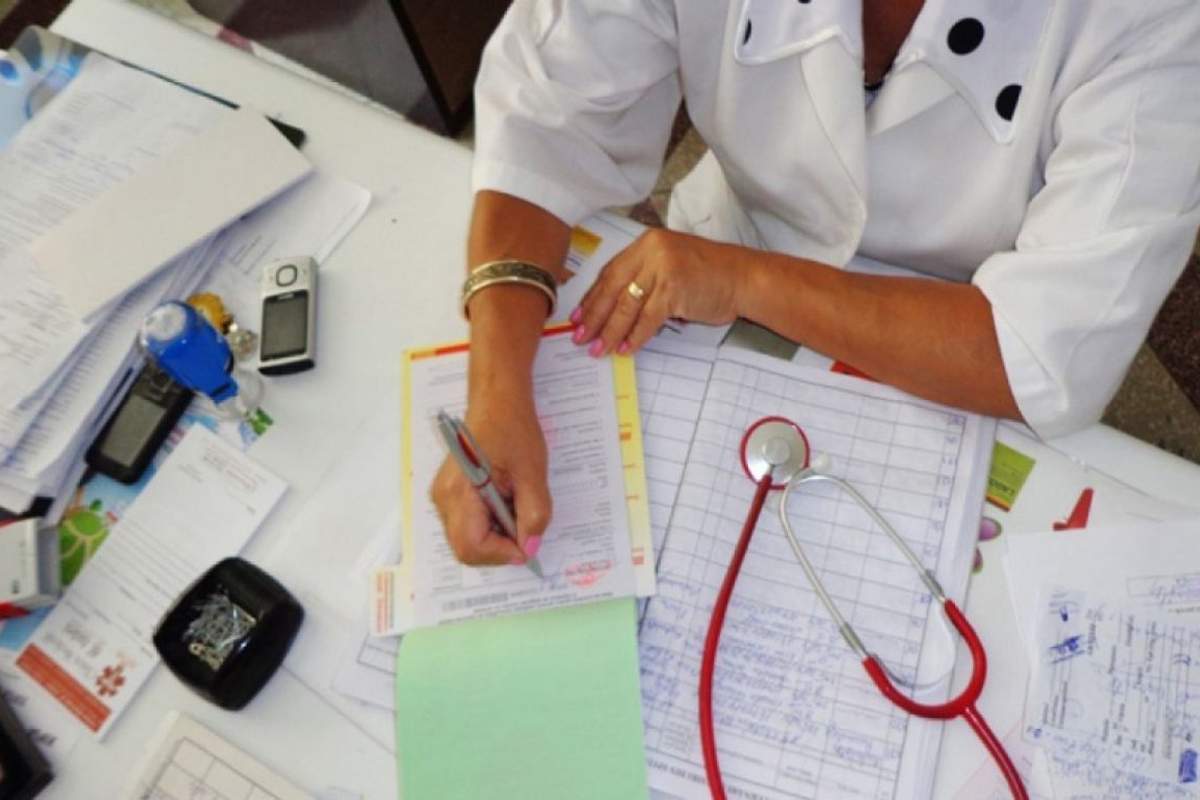 Doctoriță semnează un formular de concediu medical