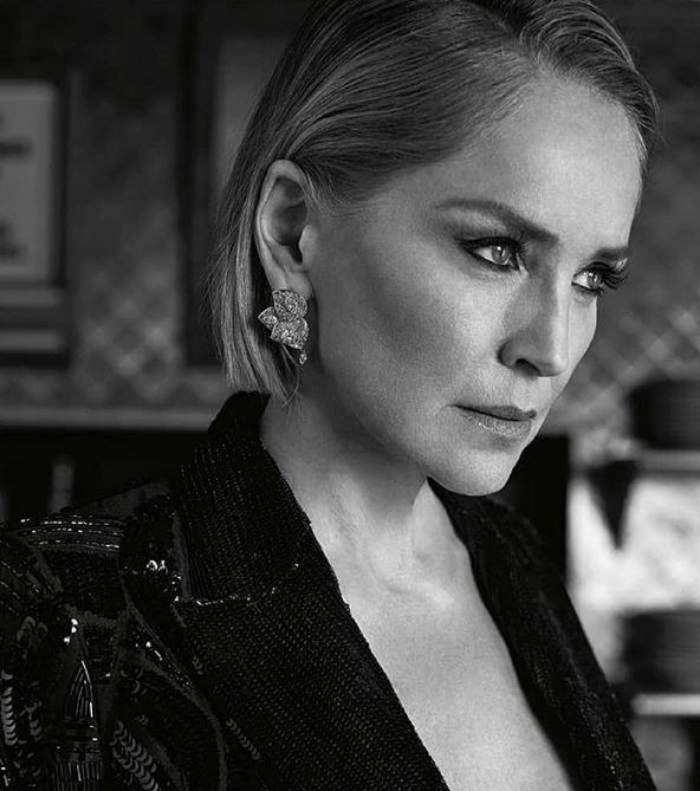 Sharon Stone intr-o fotografie alb-negru, poarta un sacou negru, fiind goala pe sub