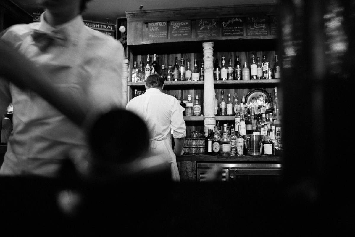 Imagine alb negru cu barmani și oameni într-un bar