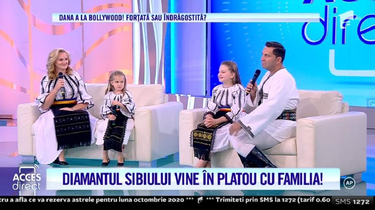 Robert Târnăveanu alături de soție și de fiicele lor. Cei patru stau pe canapele, îmbrăcați în port popular.