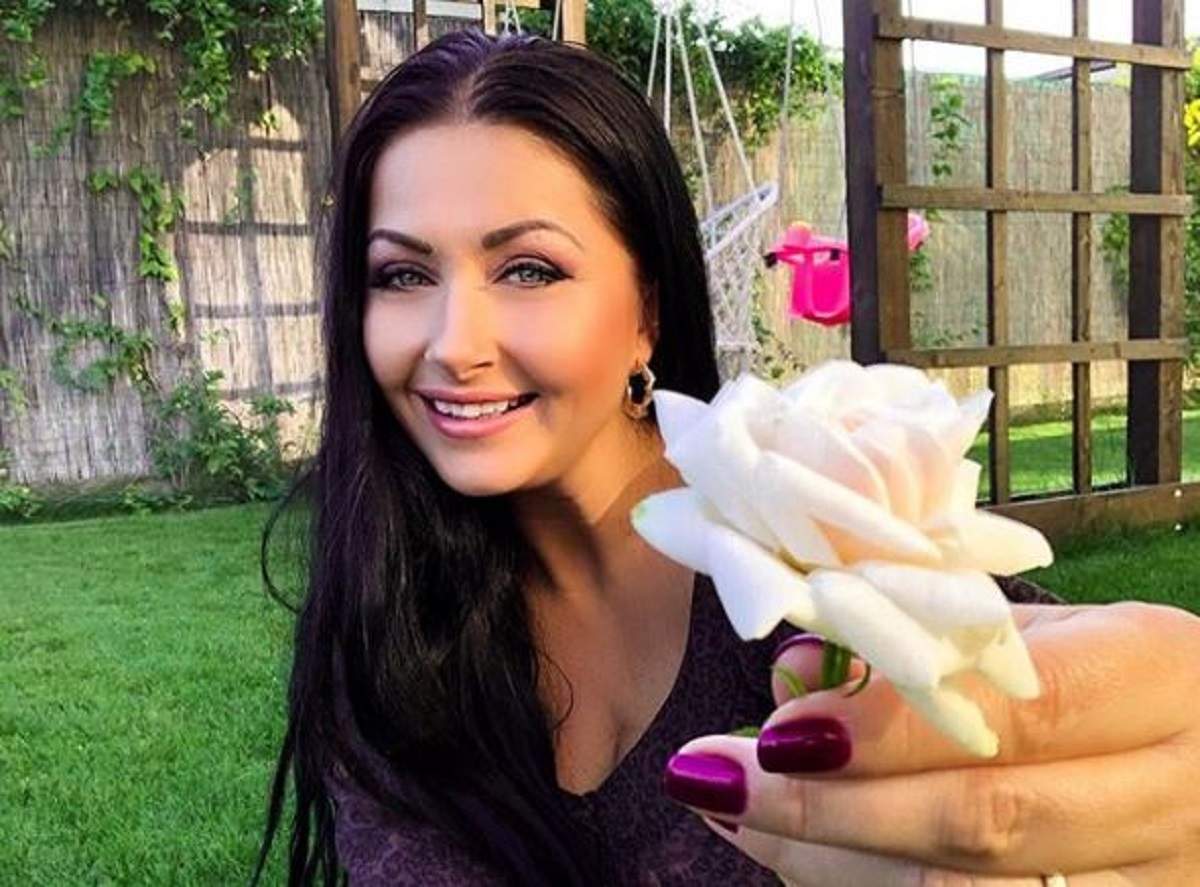 Gabriela Cristea este în curtea casei sale. Vedeta are în mână o floare și zâmbește.