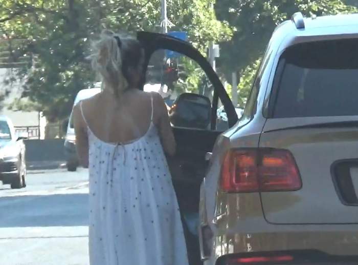 Soția lui Mirel Rădoi, purtând o rochie vaporoasă, se urcă în mașina pe care a lăsăt-o pe band de circulație, încurcând traficul