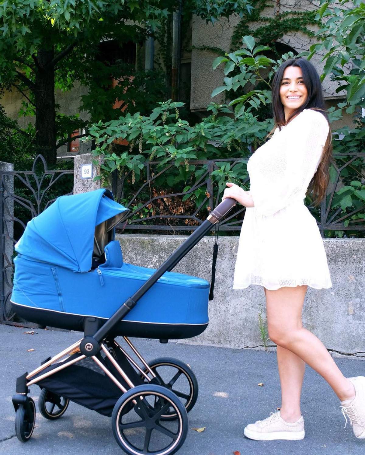 Lili Sandu, îmbrăcată într-o rochie albă, își plimbă copilul în cărucior