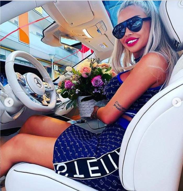 Loredana Chivu stă în noua mașină, în timp ce ține un buchet de flori în mână și zâmbește larg