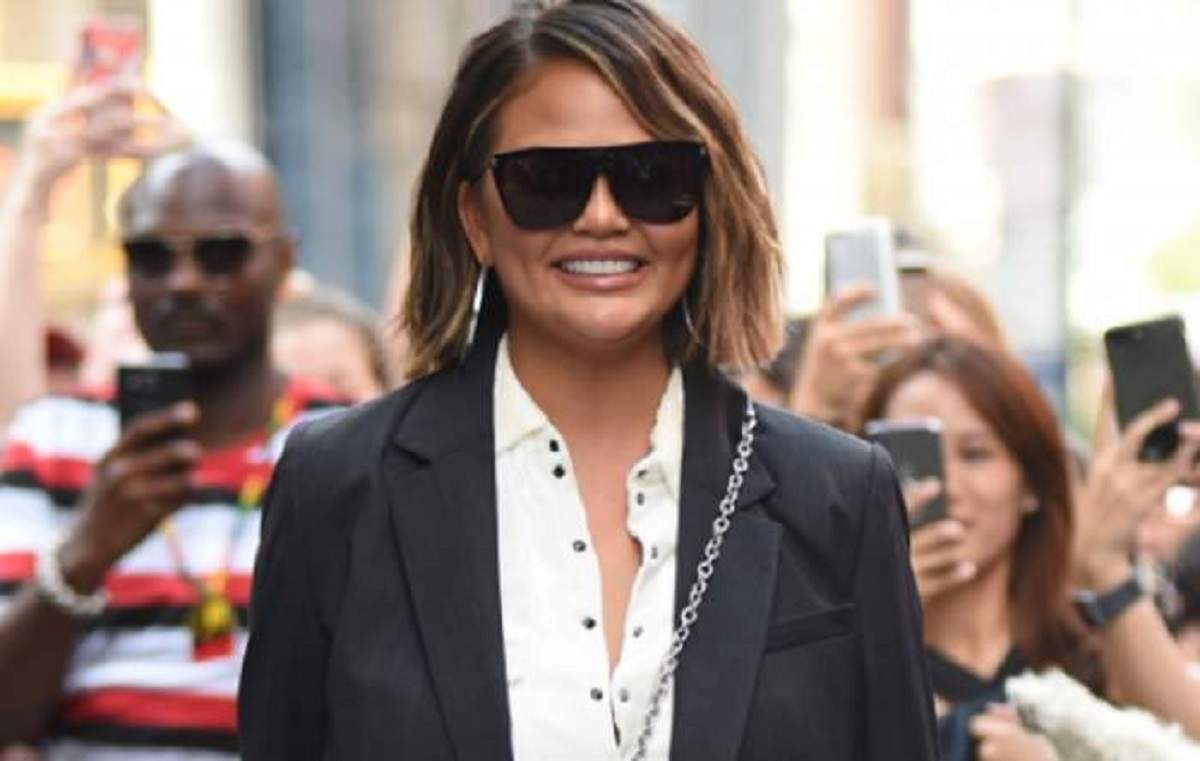 Chrissy Teigen este fotografiată pe stradă de fani, este îmbrăcată gros și zâmbește larg