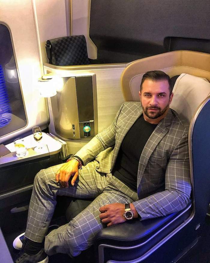 Alex Bodi, fotografiat într-un avion privat, îmbrăcat în costum și bluză neagră