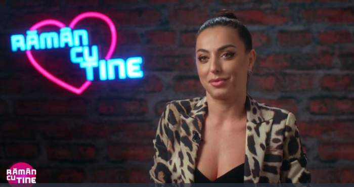 Lavinia Ilcău dă un interviu în cadrul emisiunii „Rămân cu tine”. Tânăra poartă o bluză cu animal print.