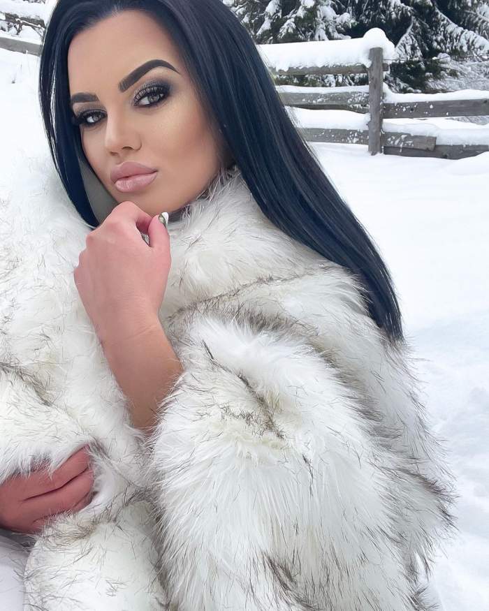 Carmen de la Sălciua se află afară, în zăpadă. Artista e îmbrăcată în haina de blană albă cu nuanțe gri.