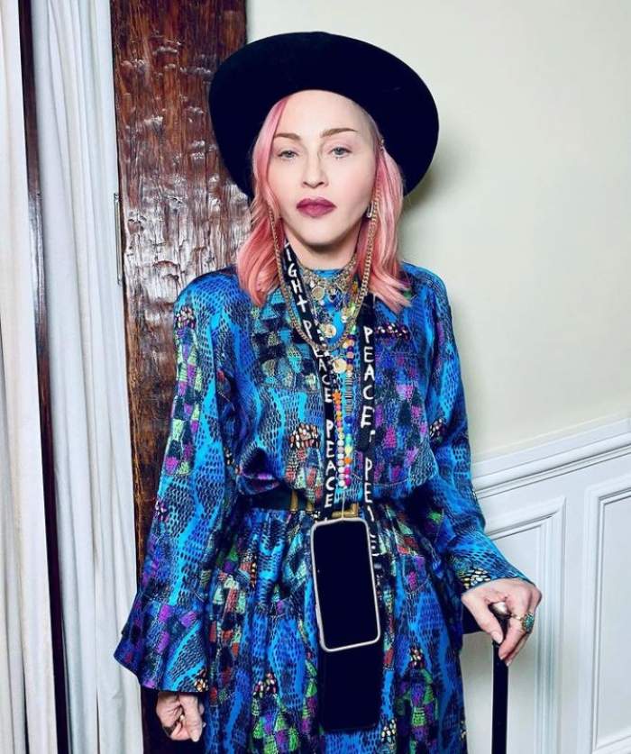 Madonna poarta un kimono cu model albastru, palarie neagra si are parul roz