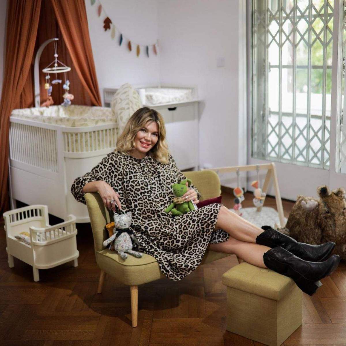 Gina Pistol, așezată pe fotoliu, lângă pătuțul copilului