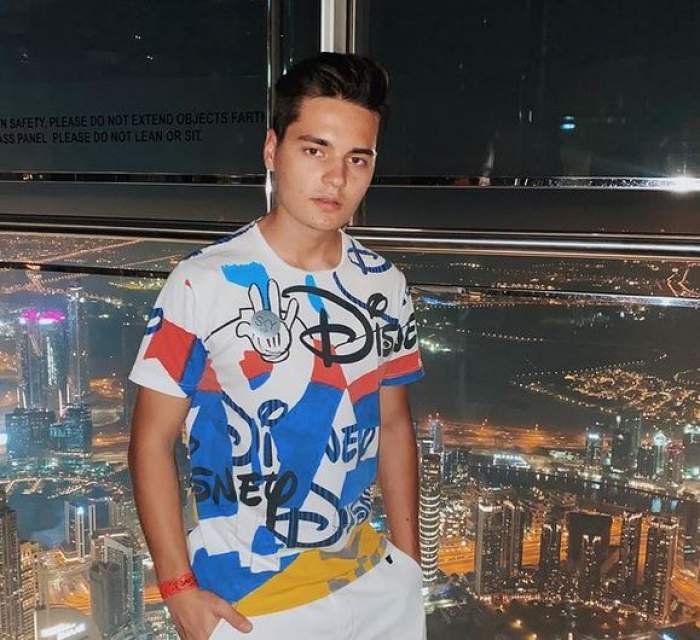 Selly se afla în vacanța din Dubai. Artistul poartă un tricou colorat și pantaloni albi.