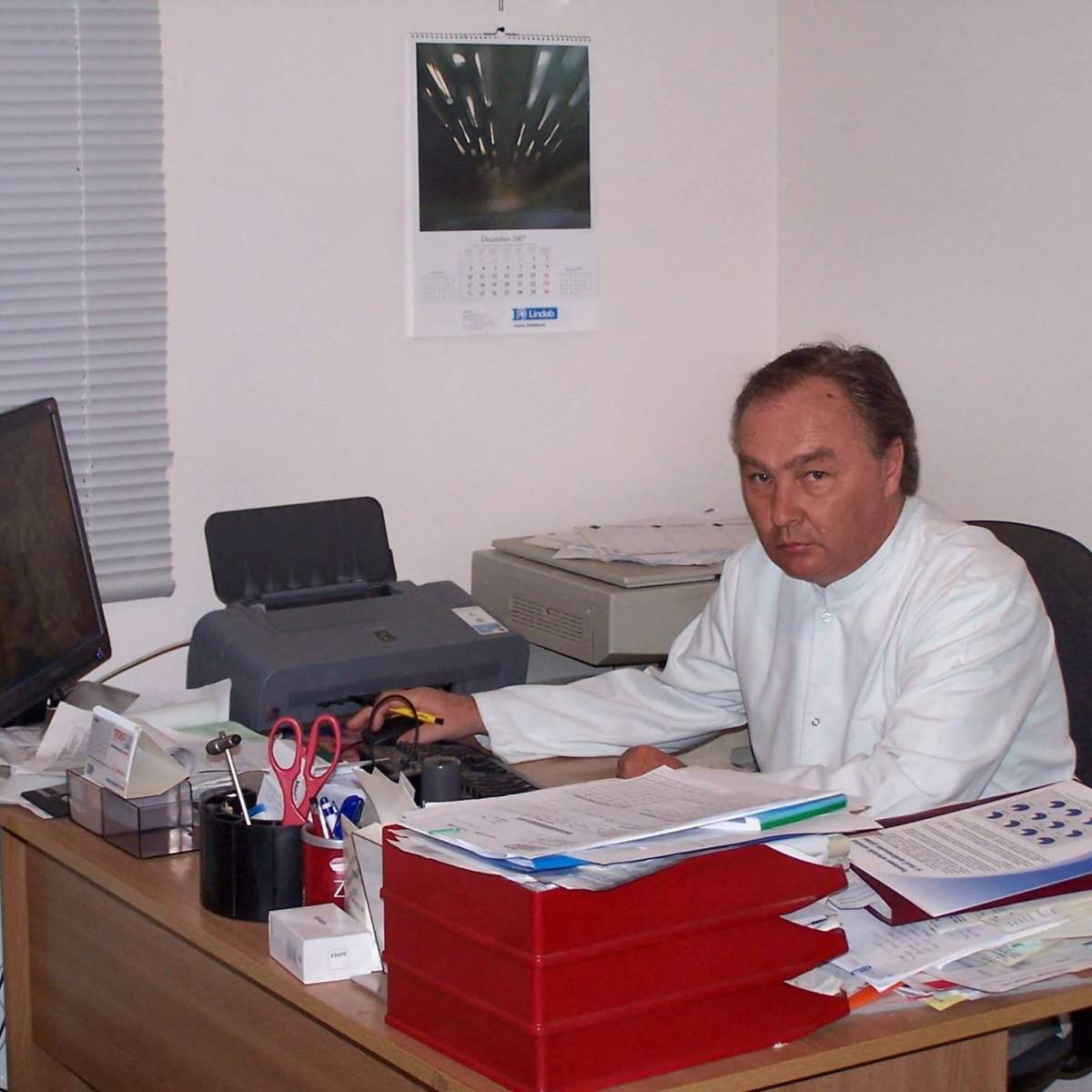 Medicul Catalin Petrencic sta la birou, poarta un halat alb