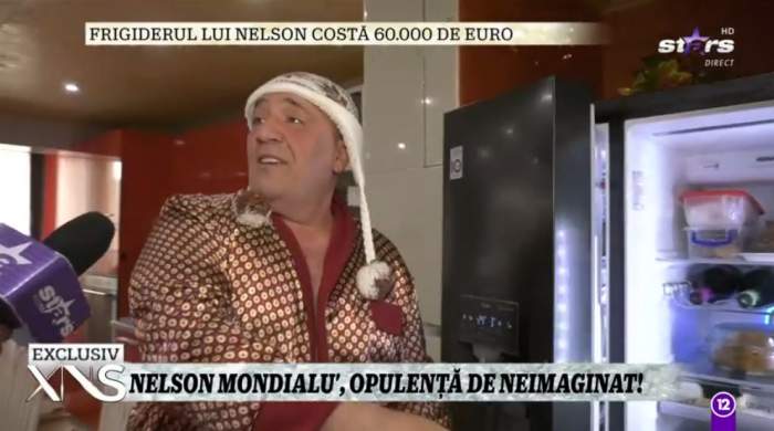 Nelson Mondialu isi arata frigiderul de acasa, poarta un halat cu animal print si fes cu franjuri in cap