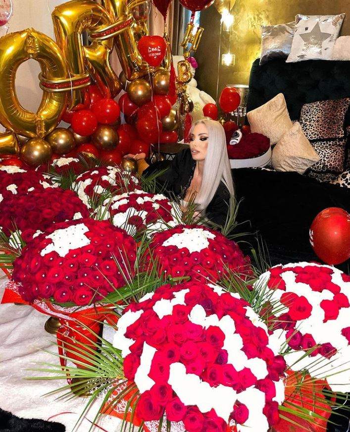 Loredana Chivu sta pe jos in dormitor, este inconjurata de trandafiri rosii si albi