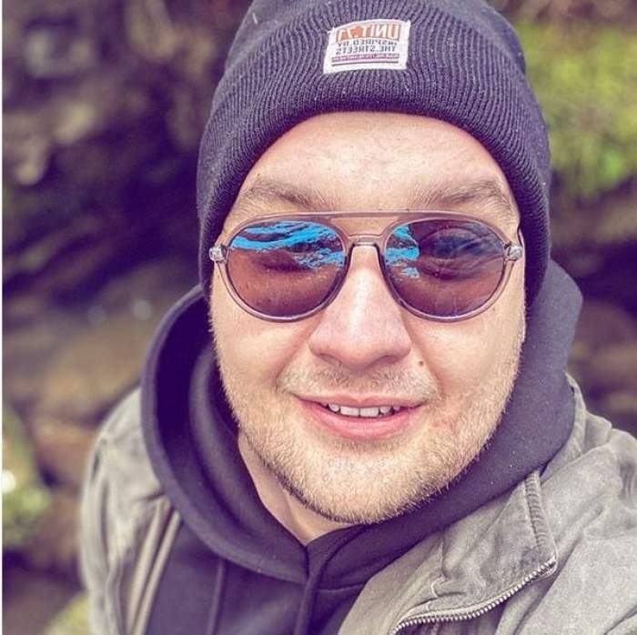 Răzvan Babană se află afară. Fostul concurent de la Chefi la cuțite își face un selfie. Tânărul poartă o căciulă și un hanorac negru, iar pe deasupra o geacă gri.