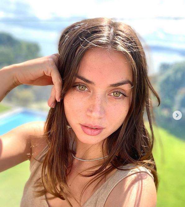 Ana de Armas se află afară. Artista își face un selfie și e îmbrăcată cu un maiou crem. Actrița își ține o mână la nivelul capului.