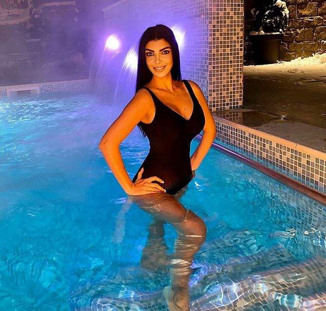 Andreea Tonciu se află în piscină. Vedeta poartă un costum de baie negru și își ține mâinile în șold.
