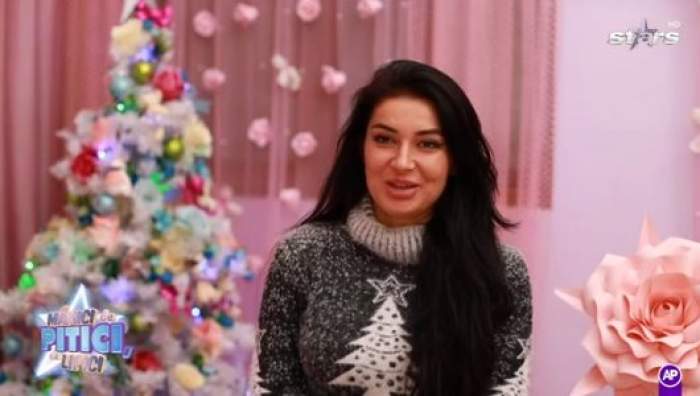 Elena Ionescu, surprinsă în timp ce oferă un interviu, având în spate un brad de Crăciu, fiind îmbrăcată într-o bluză alb cu negru