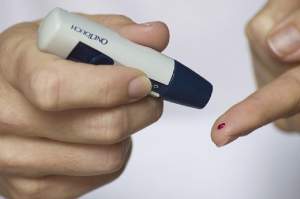 O persoană își verifică glicemia printr-o înțepătură în deget