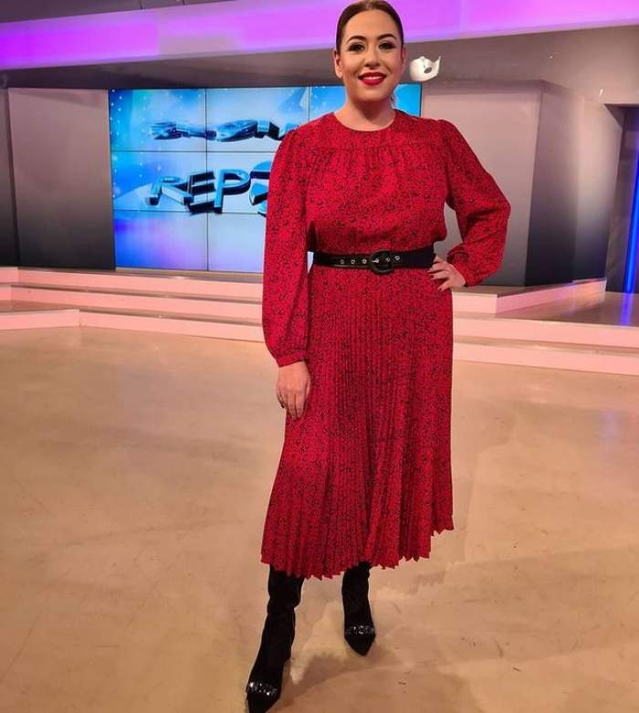 Oana Roman se află în platoul Antena Stars. Vedeta poartă o rochie roșie, cu o curea neagră la mijloc, și niște pantofi negri.