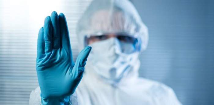 Mâna unui medic, cu mănușă, ce arată stoparea pandemiei