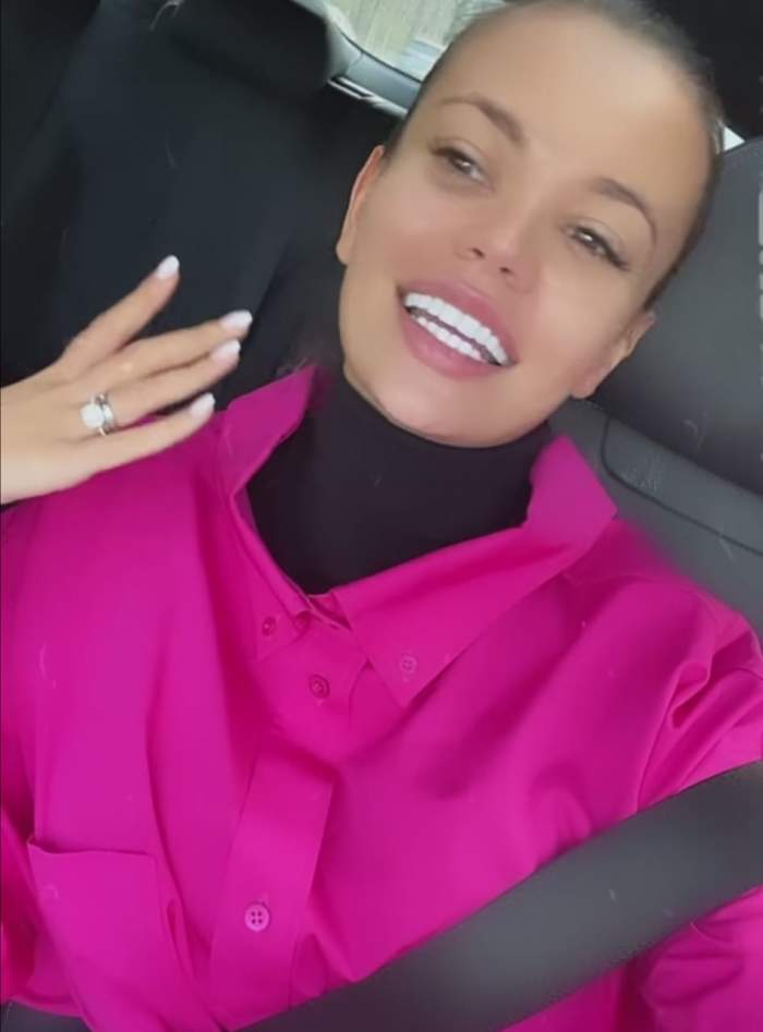 Denisa Hodișan, în mașină, zâmbitoare, îmbrăcată în roz