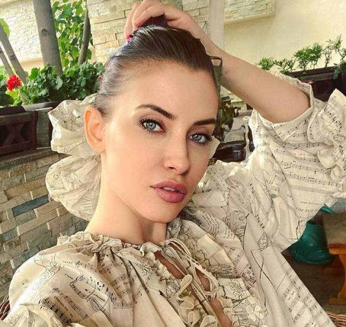 Iulia Albu își face un selfie. Vedeta poartă o cămașă crem și are părul prins în coc.