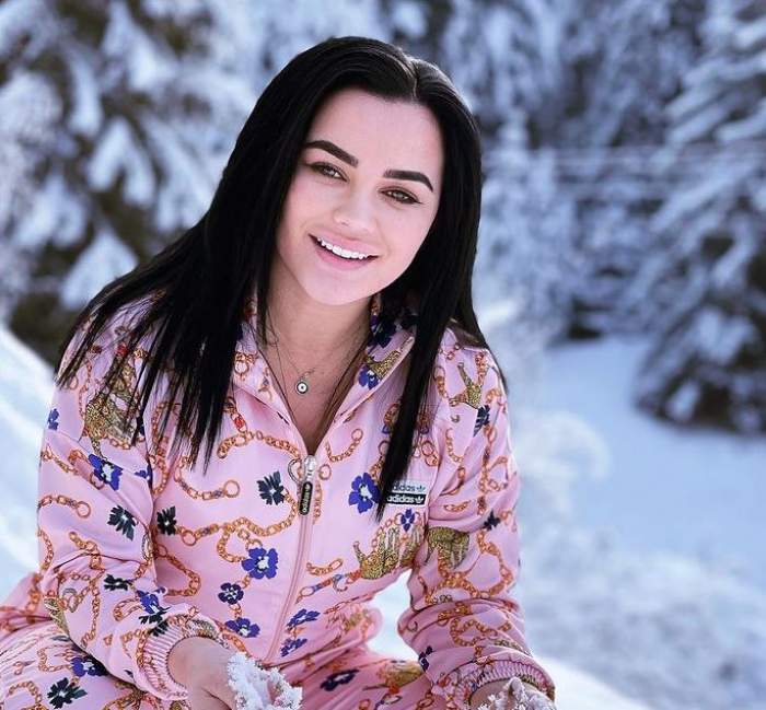 Carmen de la Sălciua se află afară, în zăpadă. Artista e îmbrăcată într-un trening roz și zâmbește larg.