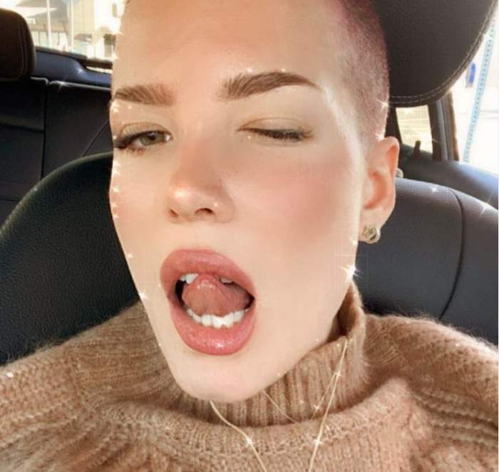 Halsey se află în mașină. Vedeta poartă un pulover maro și ține limba scoasă afară.