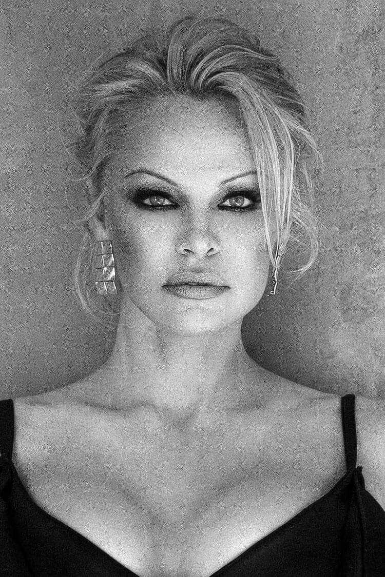 Pamela Anderson poartă o rochie neagră cu decolteu. Vedeta are părul prins în coc.