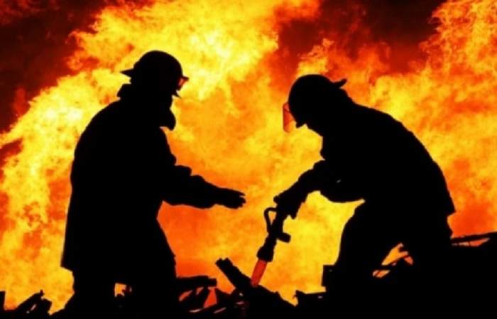 Doi pompieri care sting focul