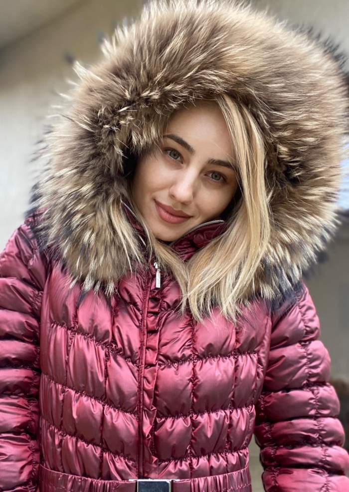 Emilia Dorobanțu poartă o geacă de iarnă roz. Vedeta se află afară și își ține gluga pe cap.