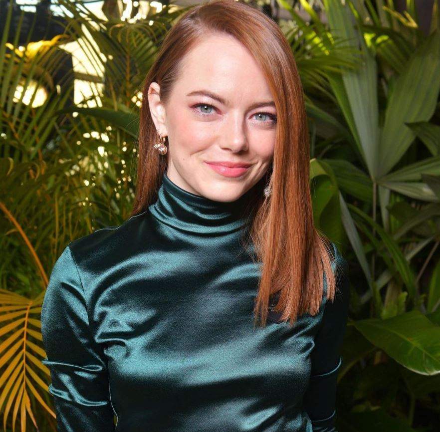 Emma Stone este la un eveniment, poarta o rochie din satin verde, are parul desprins