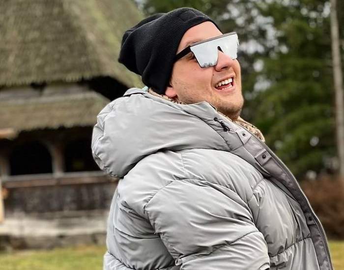 Răzvan Babană se află în vacanță, la Maramureș. Tânărul poartă un fes negru, ochelari de soare și geacă de iarnă gri.